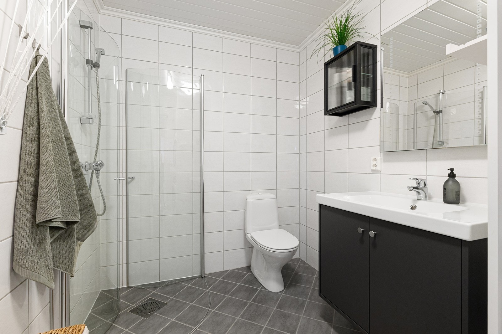 Badet er innredet med servant i baderomsinnredning, speil med belysning, toalett, dusjhjørne og opplegg for vaskemaskin. Galleribilde