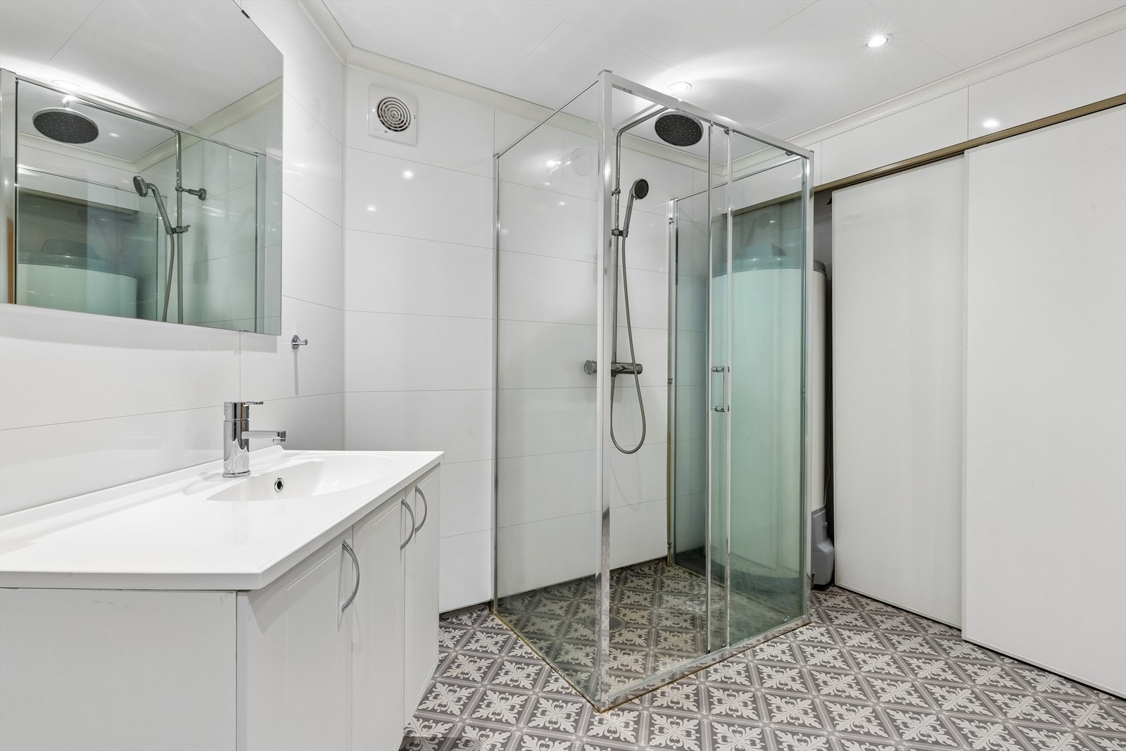 Badet har gulvvarme, vegghengt toalett og dusj med glassvegger. Praktisk skyvedørsgarderobe hvor mye av det tekniske er plassert. Galleribilde