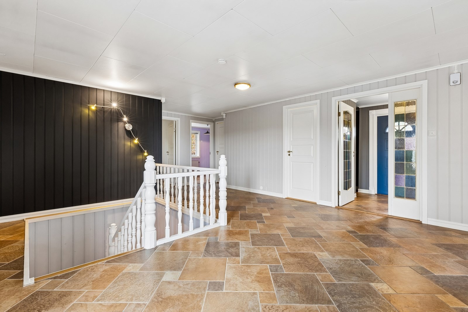 Den sentrale hallen i første etasje fordeler tilgangen til etasjens mange rom og har trapp ned til underetasjen. Galleribilde