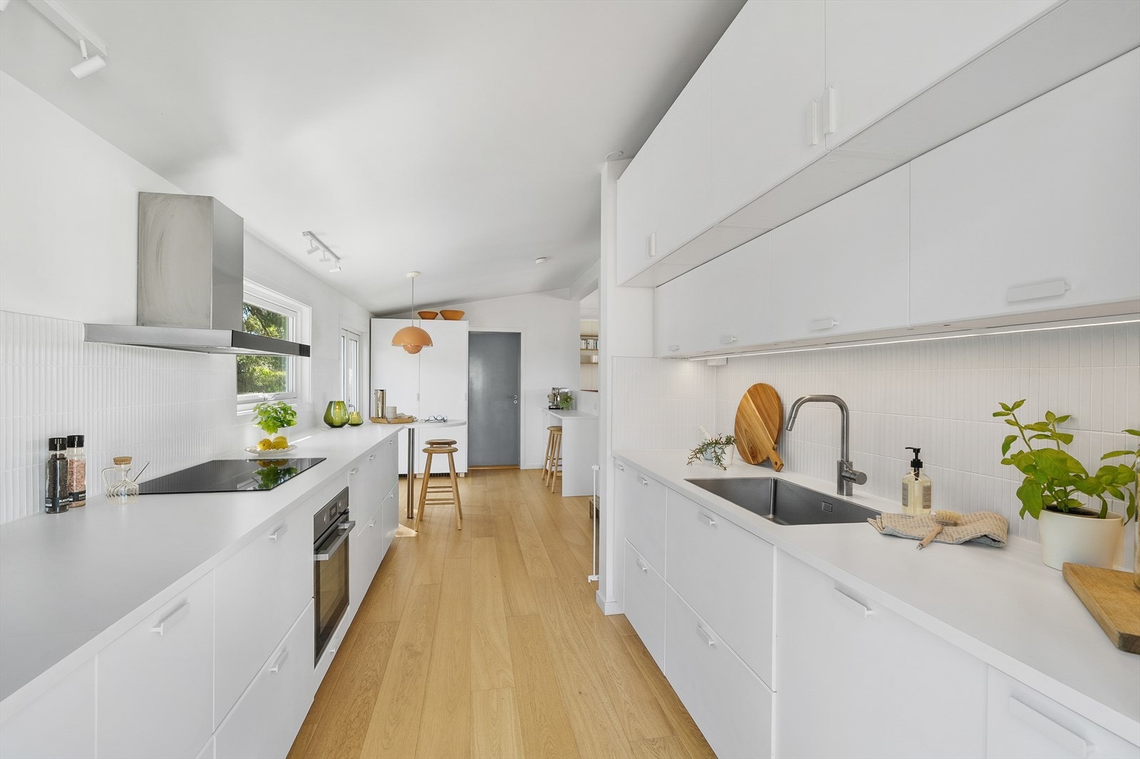 Nyere innredning fra 2023 med hvite, glatte fronter, minimalistiske håndtak og matchende benkeplate. Galleribilde
