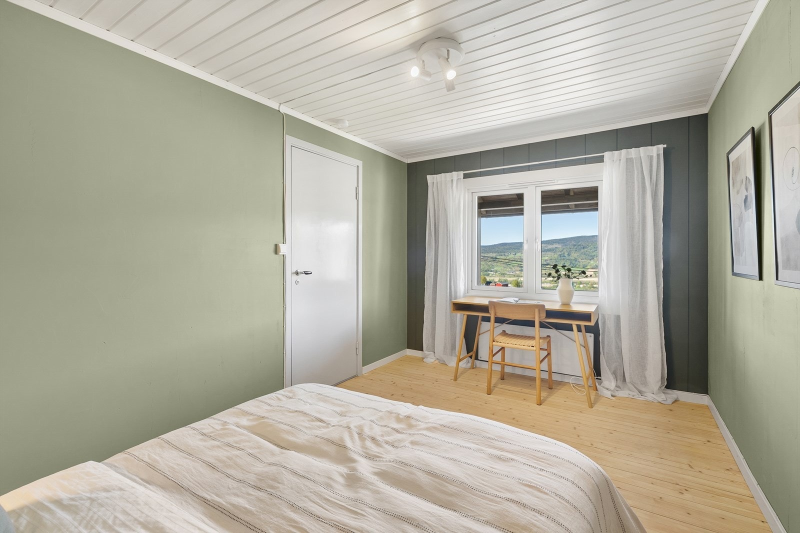 Et romslig soverom med tregulv, malte veggflater i grønntoner og hvitmalt panel i taket. Galleribilde