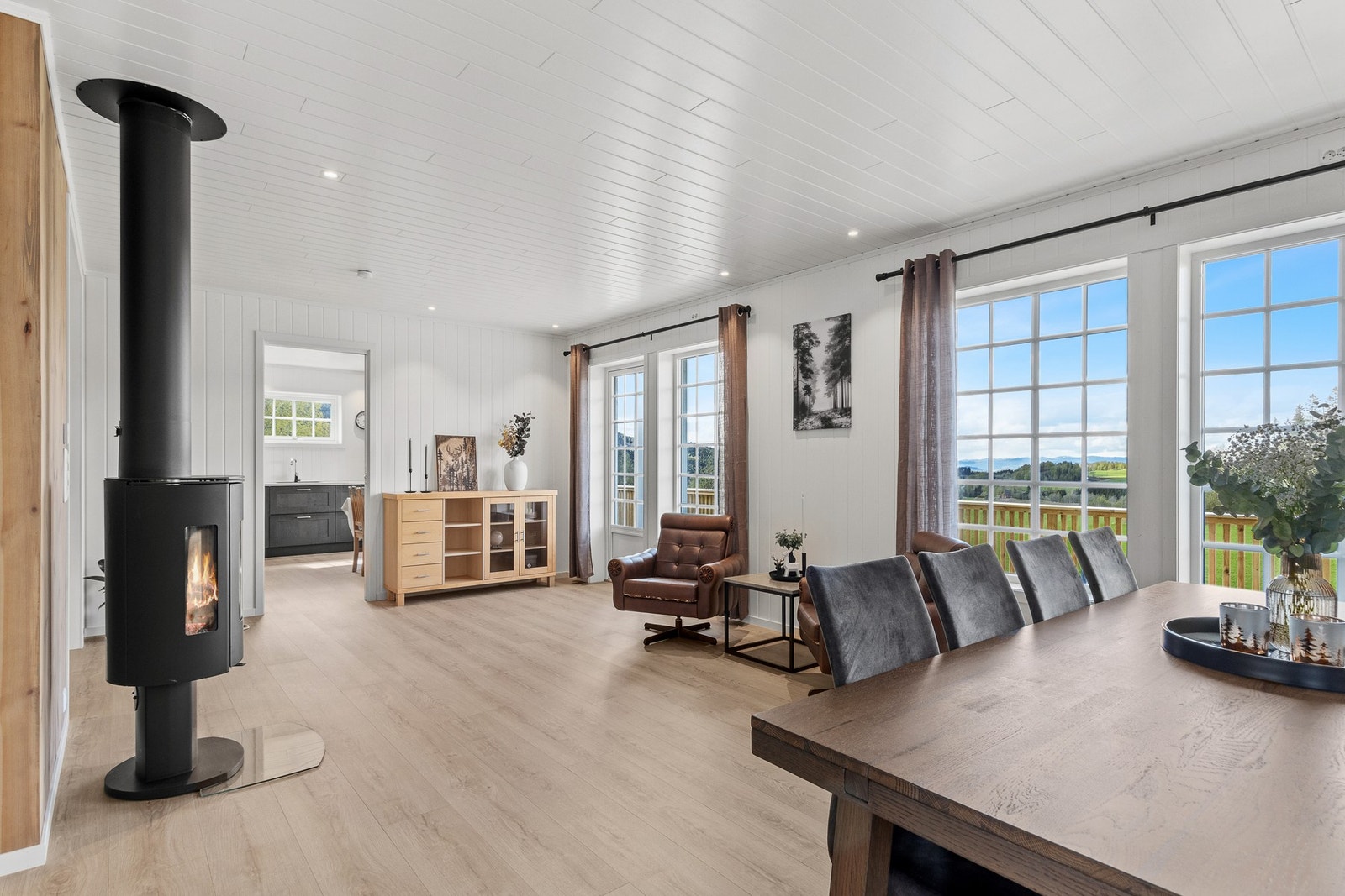 Romslig stue med spotter i tak, store vindusflater som slipper inn godt med naturlig lys og plater på vegg. Galleribilde