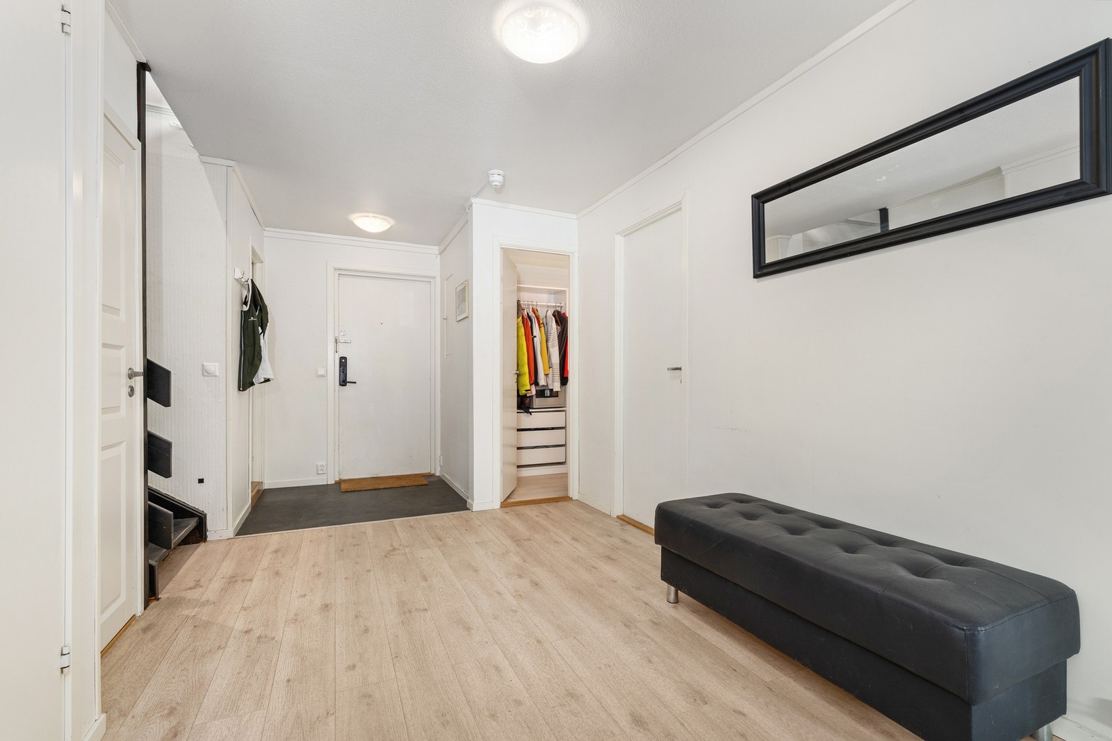 Hallen gir tilgang til en praktisk garderobe innredet med et omfattende hyllesystem med klesoppheng og skuffeseksjoner Galleribilde