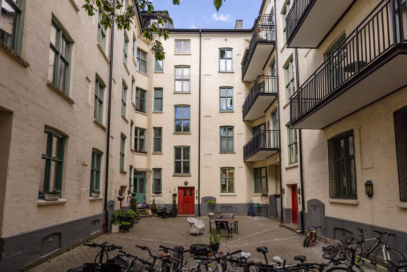 Bakgård med sittegrupper og sykkelparkering. Gården har et eget rom til plassering av barnevogner. Galleribilde