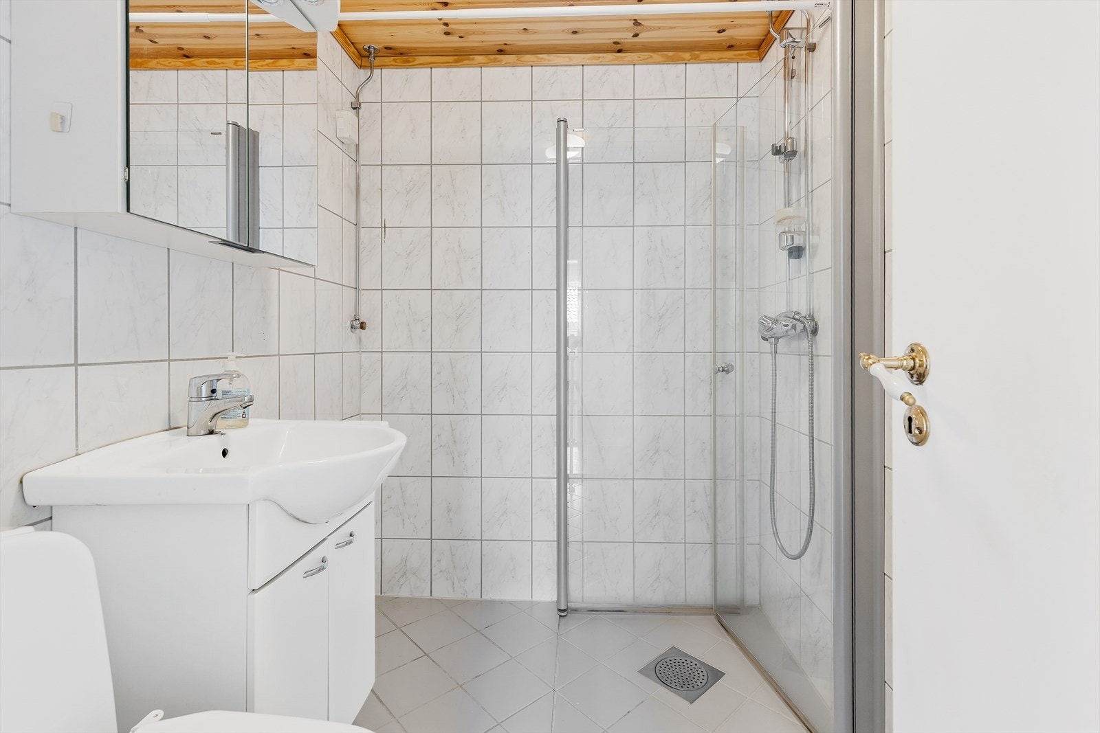 Badet er innredet med servantskap, speilskap, dusjhjørne, toalett og opplegg for vaskemaskin. Galleribilde