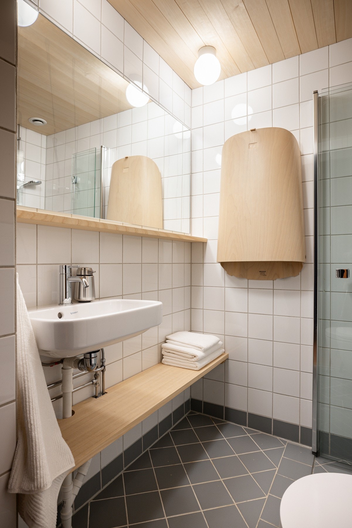 Baderommet har grå fliser på gulv, deilig gulvvarme, hvite fliser på veggene og himling i osp. Galleribilde