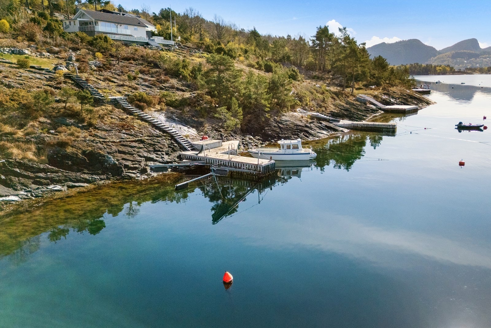 Fra eiendommen fører en trapp i naturstein og tre ned til sjøen og bryggene. Galleribilde