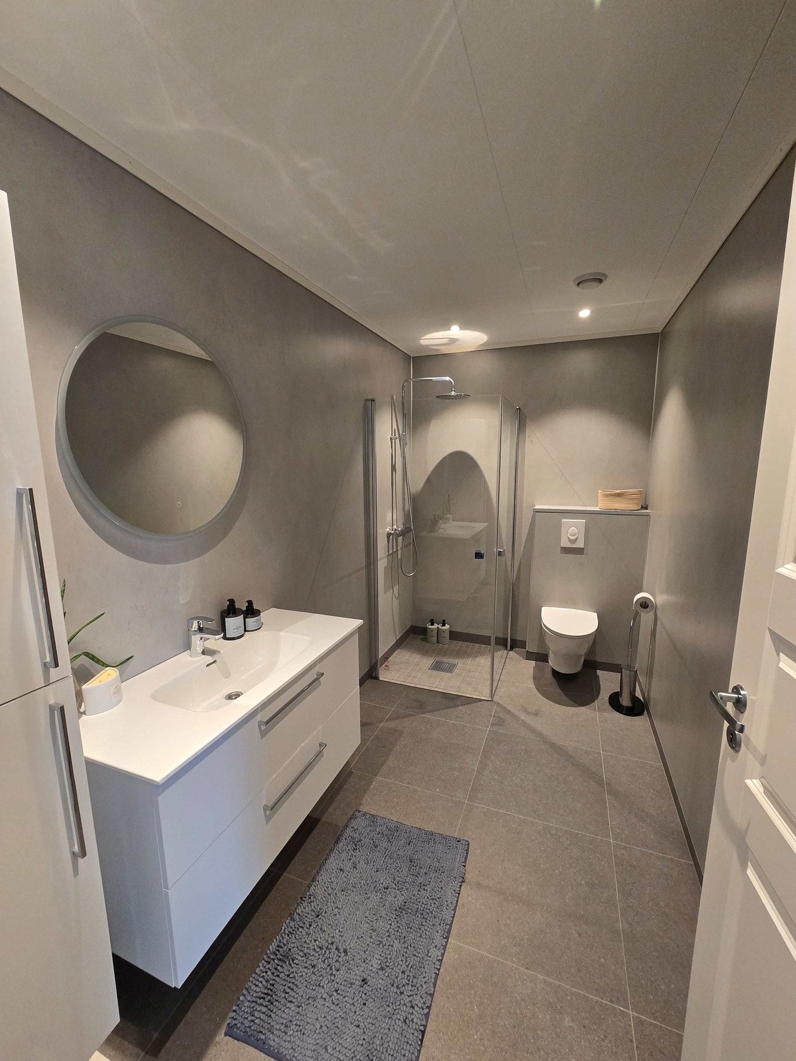 Lyst og romslig bad med fliser og Fibo Trespo baderomsplater på vegg. Downlights i taket. Galleribilde