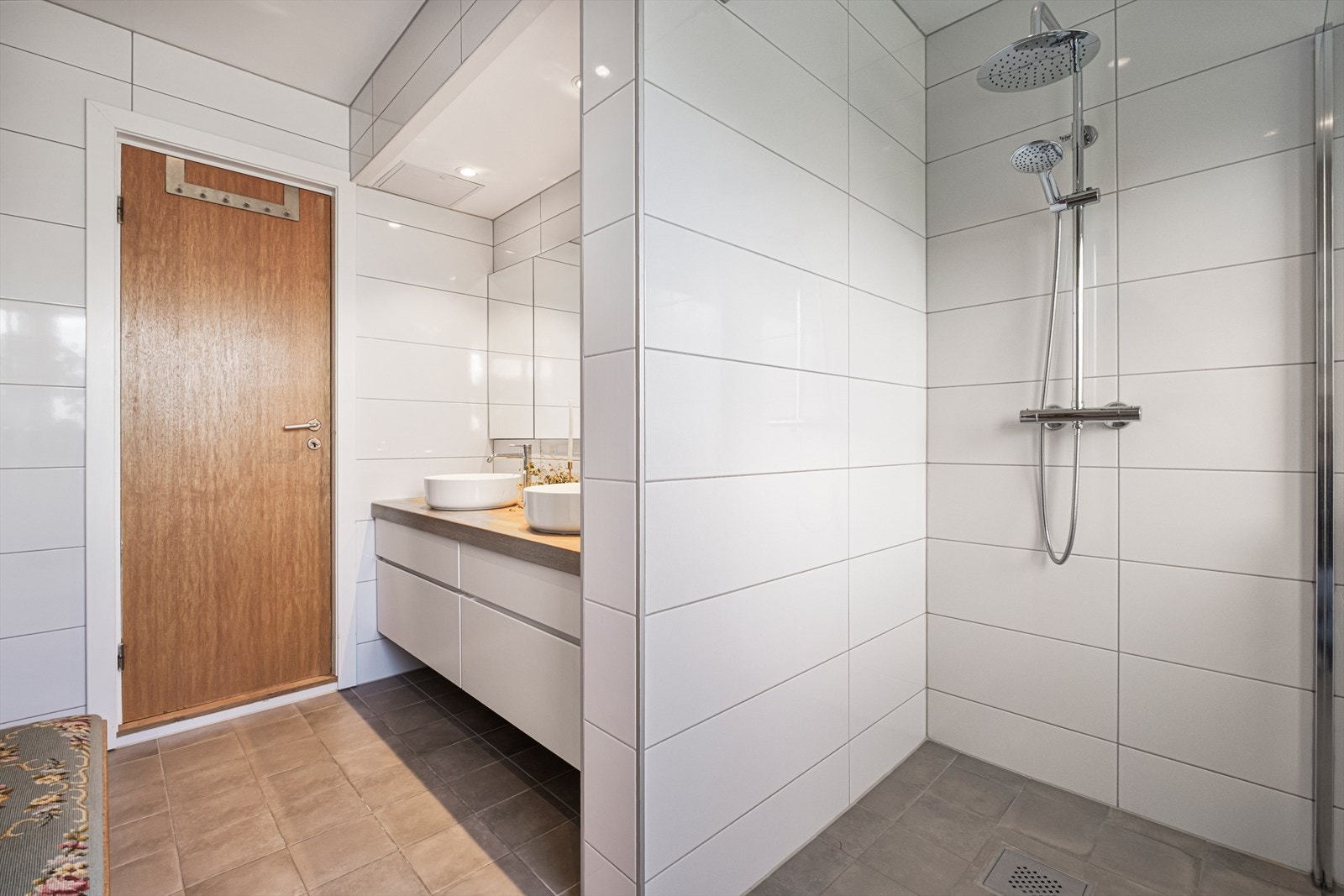 Badet har innredning med 2 servanter, vegghengt toalett og dusjnisje med glassvegg. Det er elektrisk styrt vifte Galleribilde