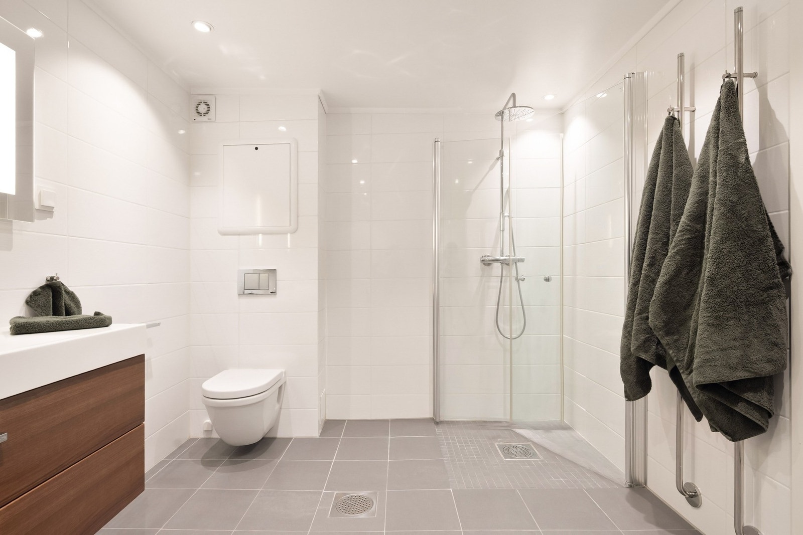 Videre inneholder badet vegghengt toalett og dusjhjørne med inn-/utadslående dører i herdet glass. Galleribilde
