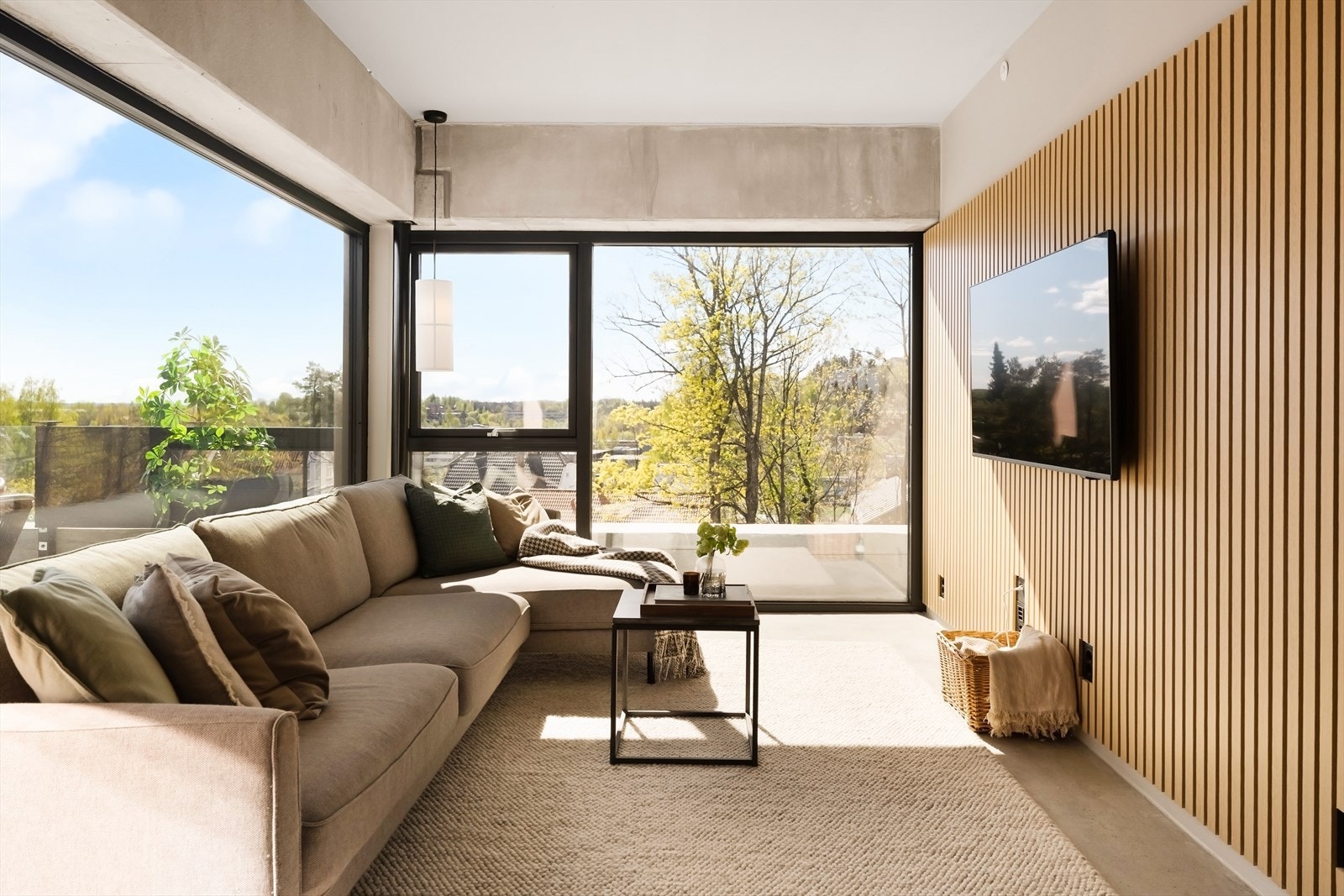 Rommet har betonggulv, malte vegger og himling, og en spilevegg som gir et moderne uttrykk og en naturlig plassering av TV-sone. Store vindusflater slipper inn rikelig med lys og gir fin utsikt, samtidig som det er direkte utgang til takterrasse. Galleribilde