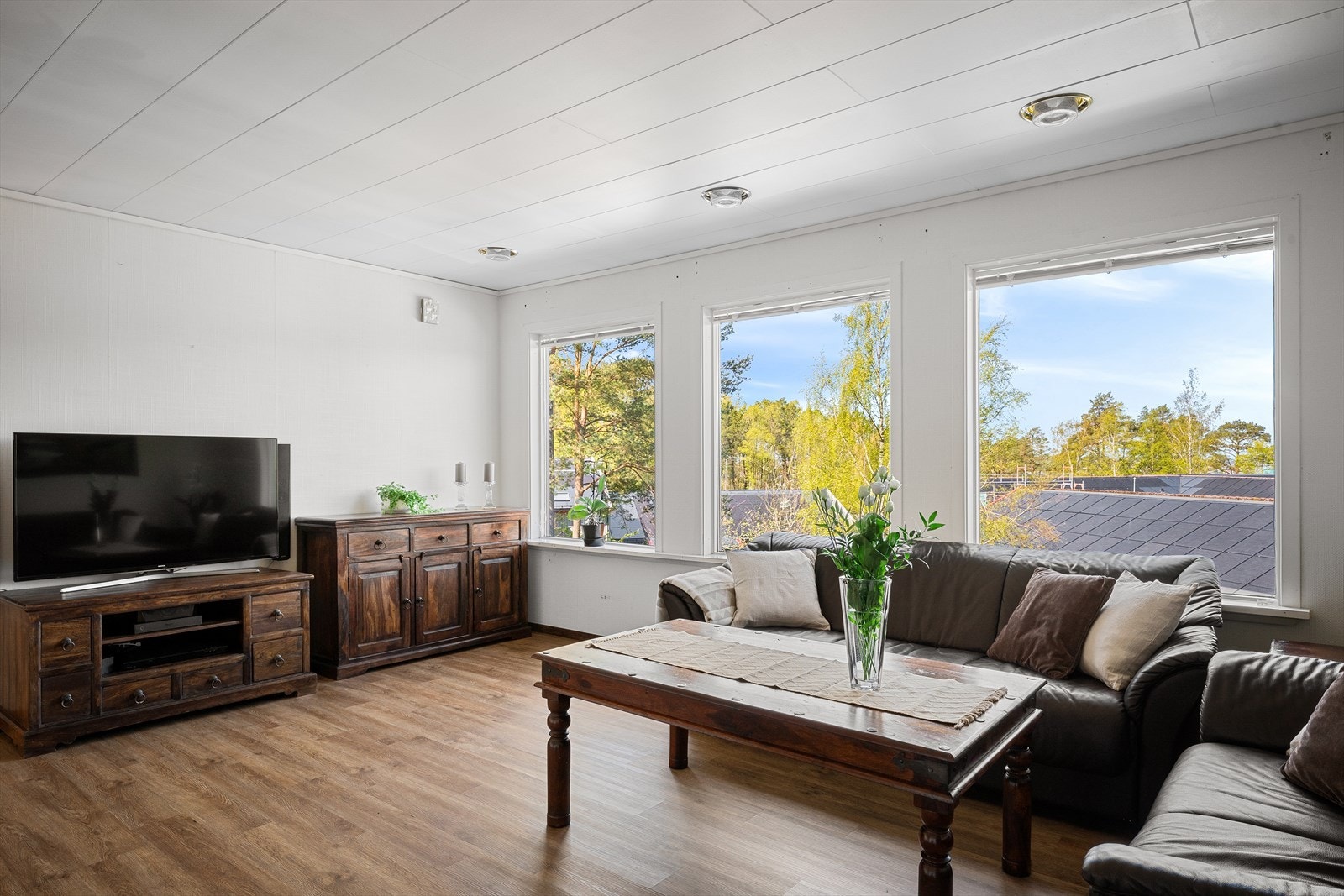 Romslig stue med plass til en stor sofagruppe og med laminat på gulvet. Galleribilde