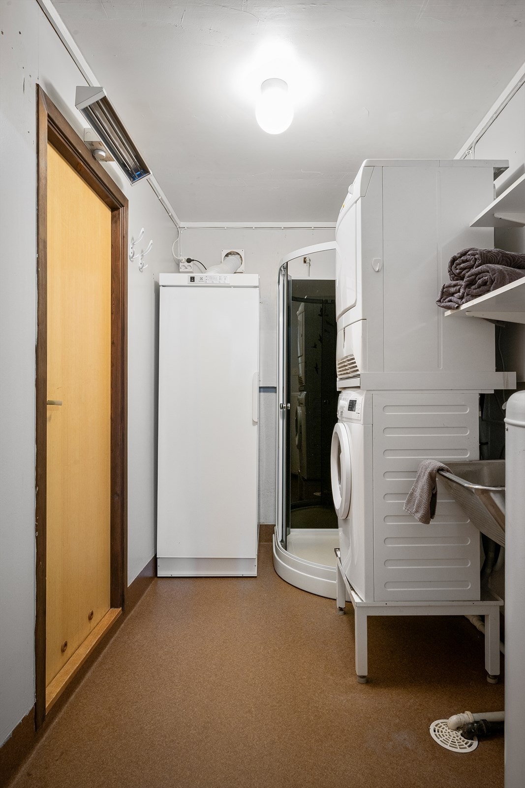 Praktisk vaskerom med dusjkabinett, utslagsvask og opplegg for vaskemaskin. Galleribilde