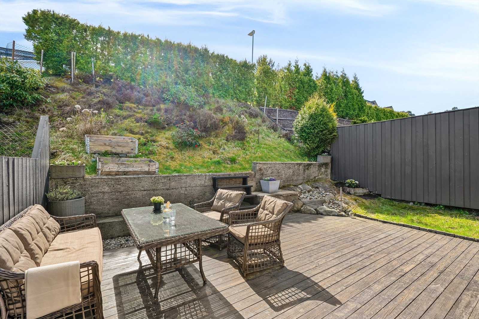 Uteplassen er opparbeidet med terrasse i trekonstruksjon og forstøtningsmurer i betong. Galleribilde