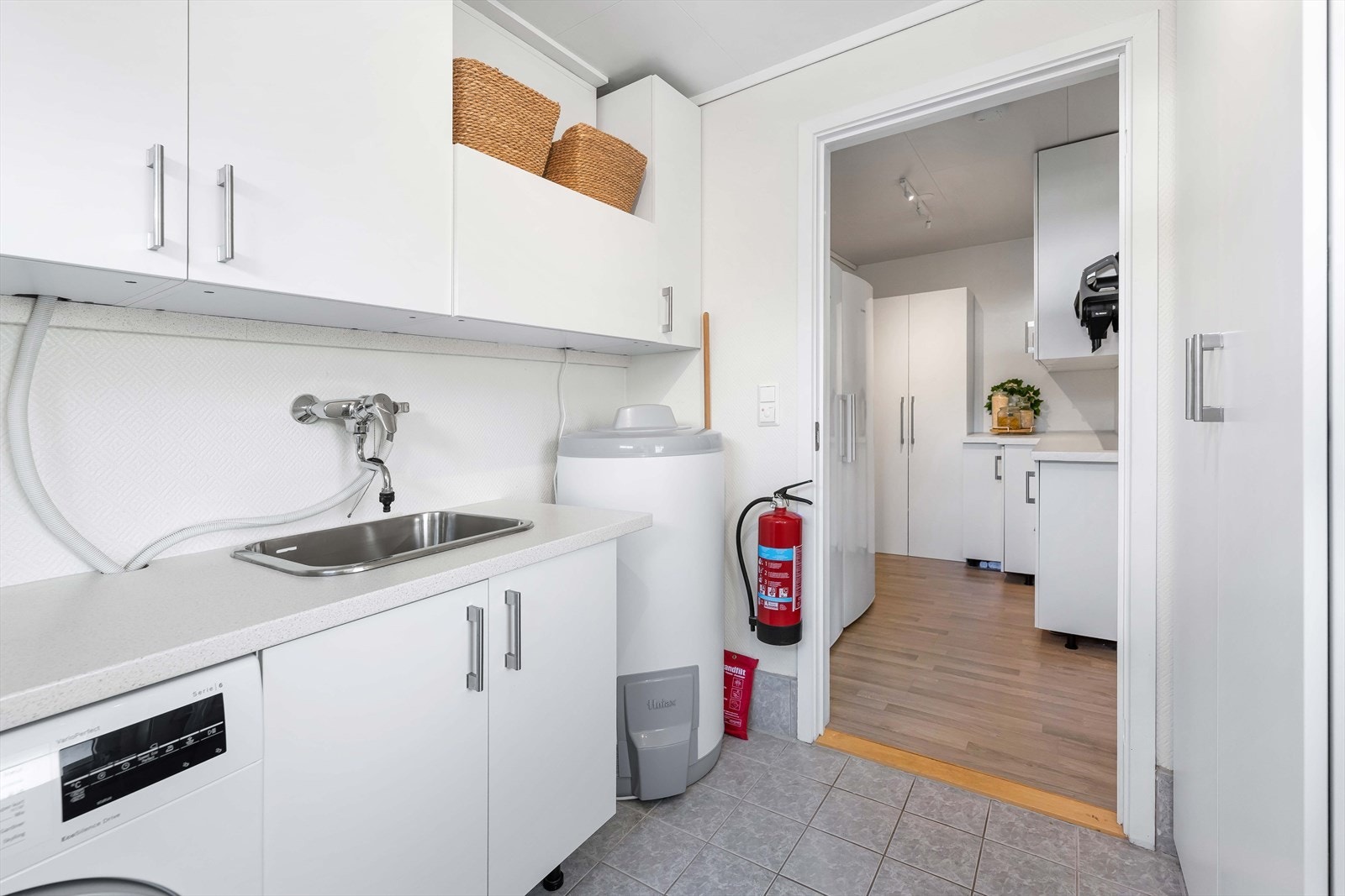 Vaskemaskin og tørketrommel har fått sin plass under benkeplaten og i selve platen er et skyllekar nedfelt. Rommets gulv er flislagt for ekstra slitestyrke. Galleribilde
