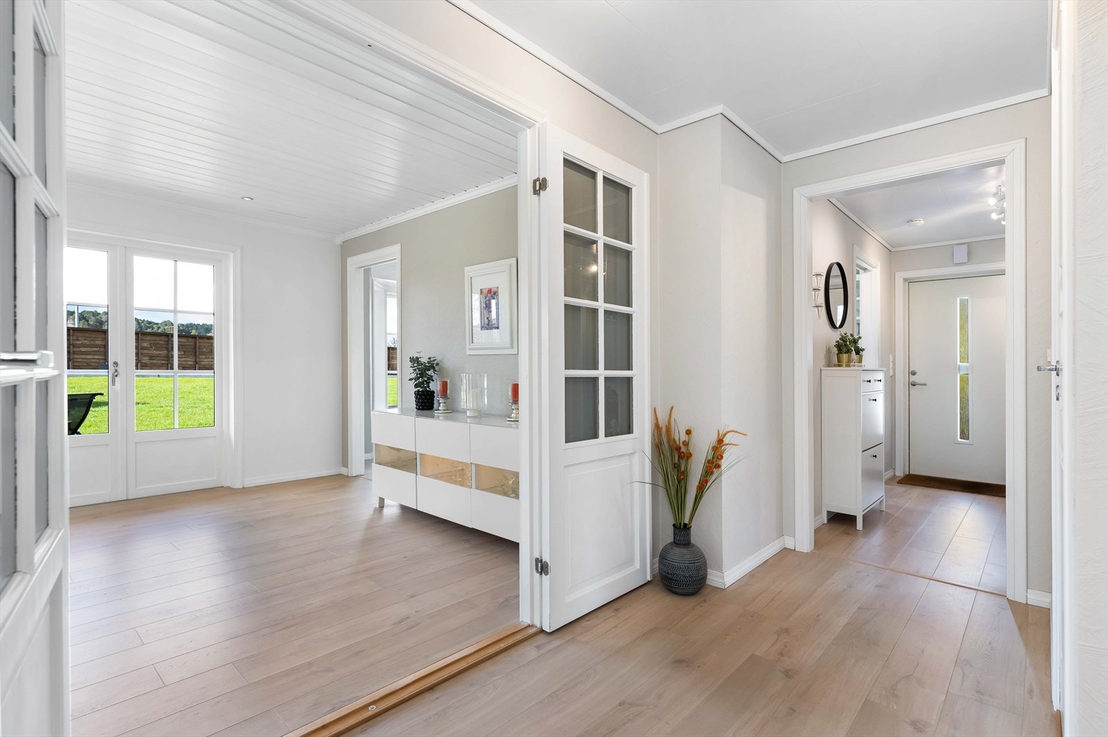 Det er også inngang til badet fra rommet samt skyvedør til kjøkkenet, dobbeltdør med glassfelt til stuen og trapp til andre etasje. Galleribilde