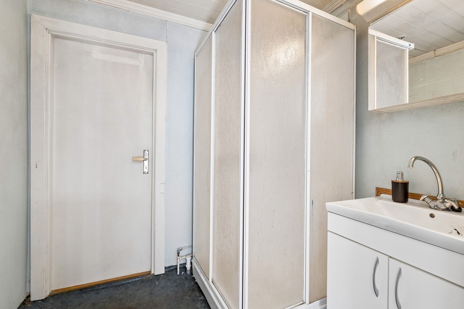 På badet er det lyst servantskap med helstøpt servantplate og overskap med speil. Det er frittstående dusjkabinett og toalett. Galleribilde