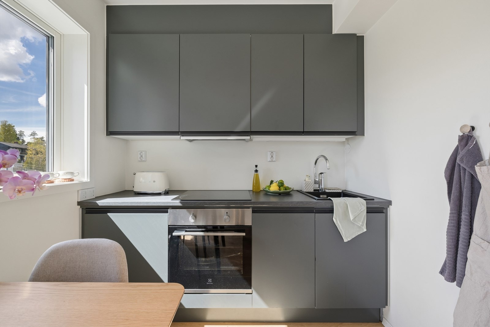 Innredningen har glatte fronter og laminat benkeplate med nedfelt vask. Integrerte hvitevarer inkluderer stekeovn, platetopp og oppvaskmaskin. Galleribilde