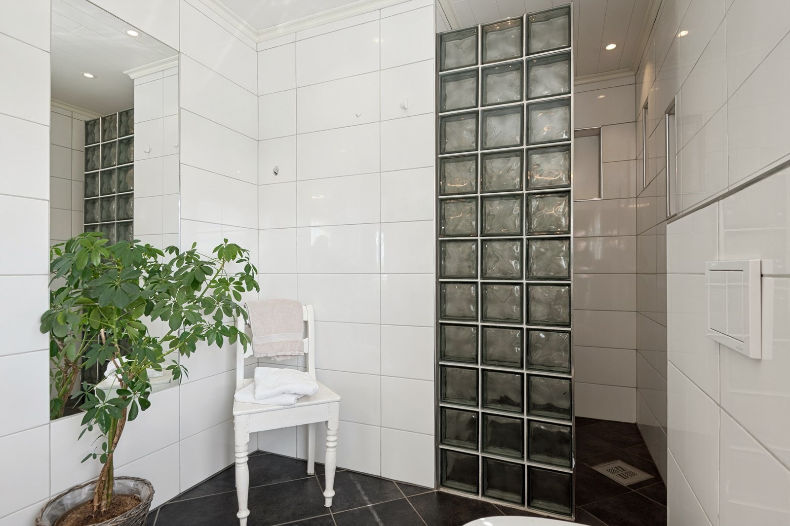 Badet har fliser på gulv med varmekabler, vegghengt toalett og et romslig dusjhjørne. Galleribilde