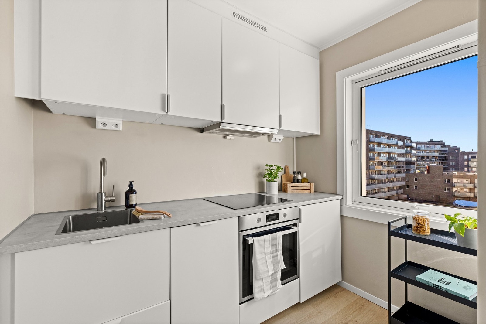 Moderne kjøkken innredning fra 2023 med glatte fronter og benkeplate i laminat. Det er integrerte hvitevarer som stekeovn, koketopp, oppvaskmaskin og kjøleskap. Galleribilde