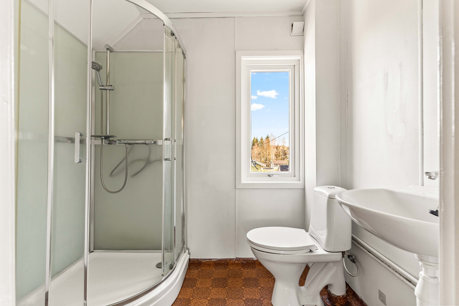 Badet er praktisk innredet med dusjkabinett, toalett og servant. Overflater består av gulvbelegg og baderomsplater. Galleribilde