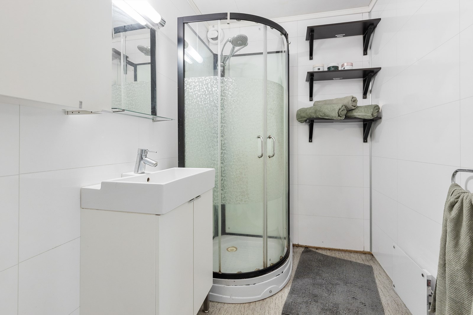 Badet i andre etasje har dusjkabinett, servant med underskap og våtromsplater på veggene. Galleribilde