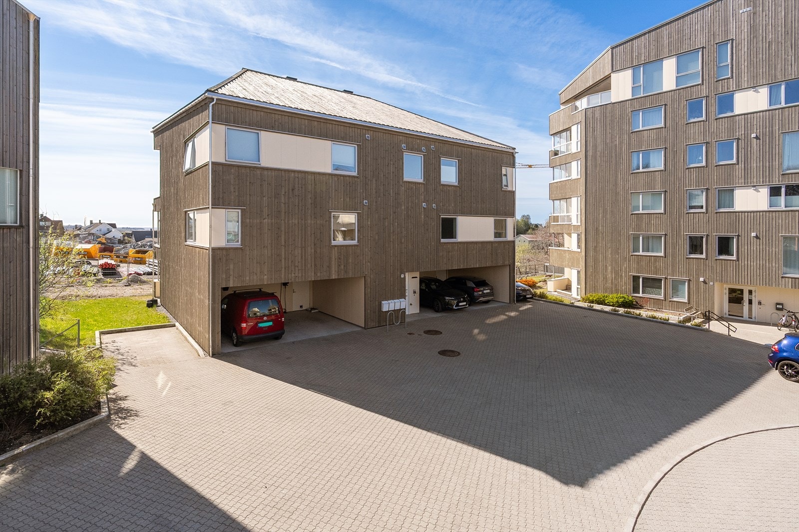 Parkeringsplass langs husvegg og i carport med elbillader som medfølger handelen. Galleribilde