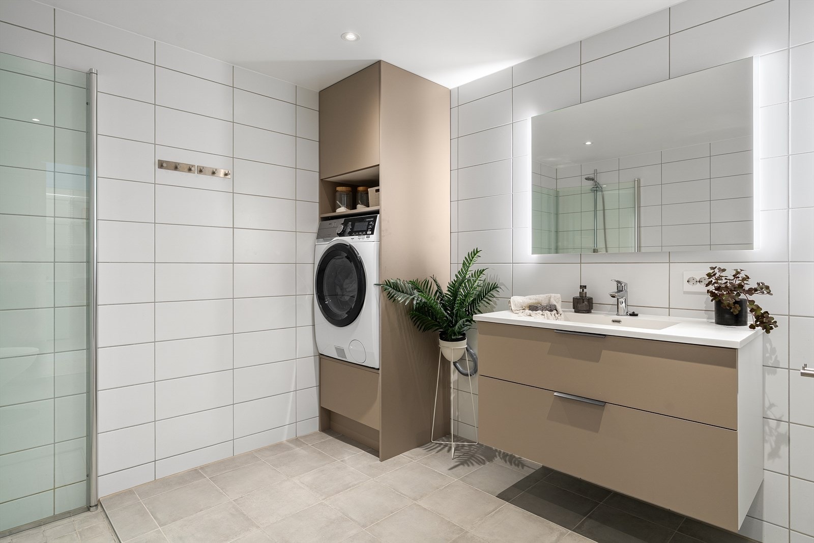 Badet har vegghengt toalett, dusjhjørne med foldbare glassvegger, speil med belysning og opplegg til vaskemaskin. Galleribilde