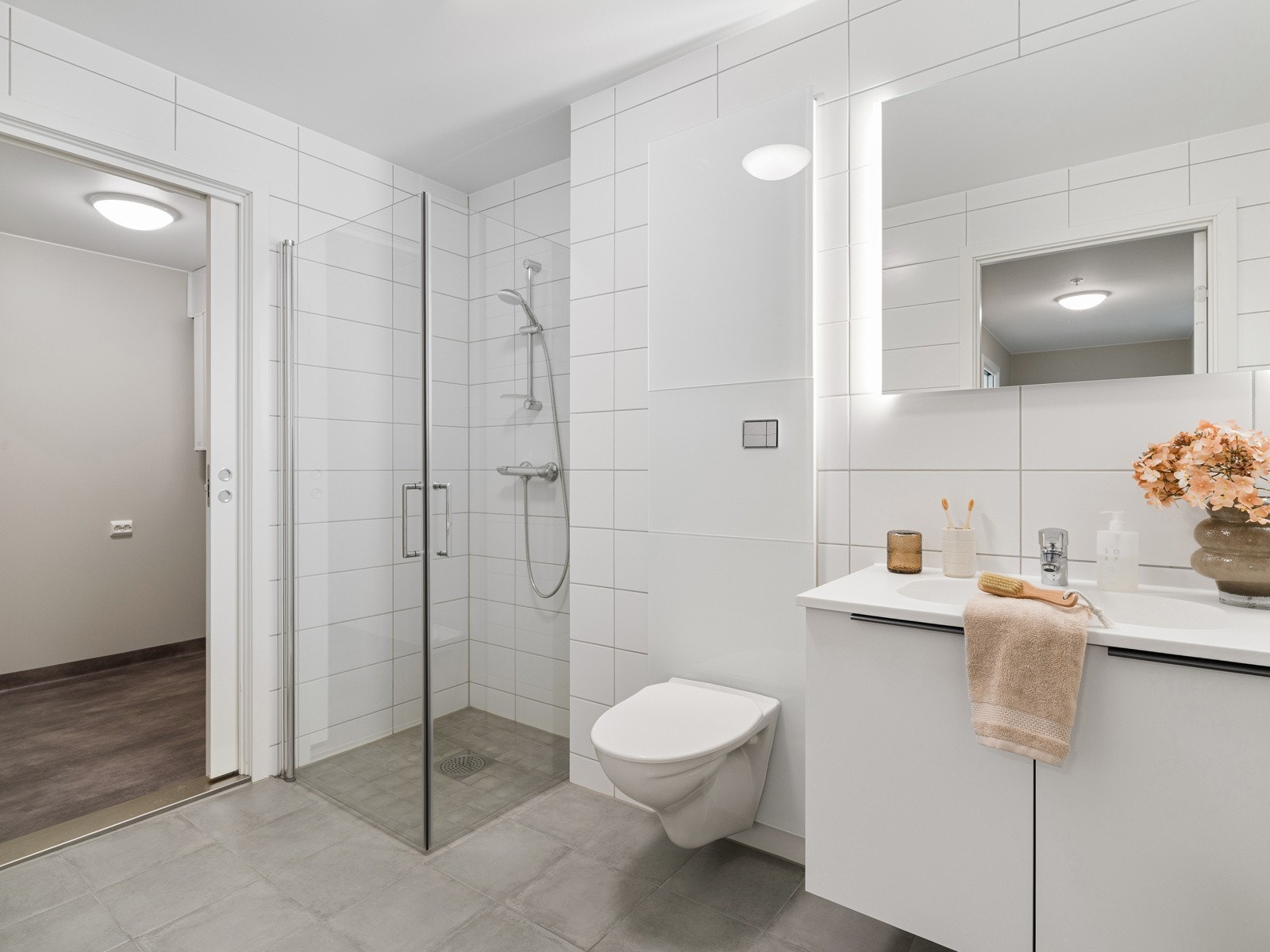 Badet har dusjhjørne med innfellbare glassdører, servant med underskap og speil Galleribilde