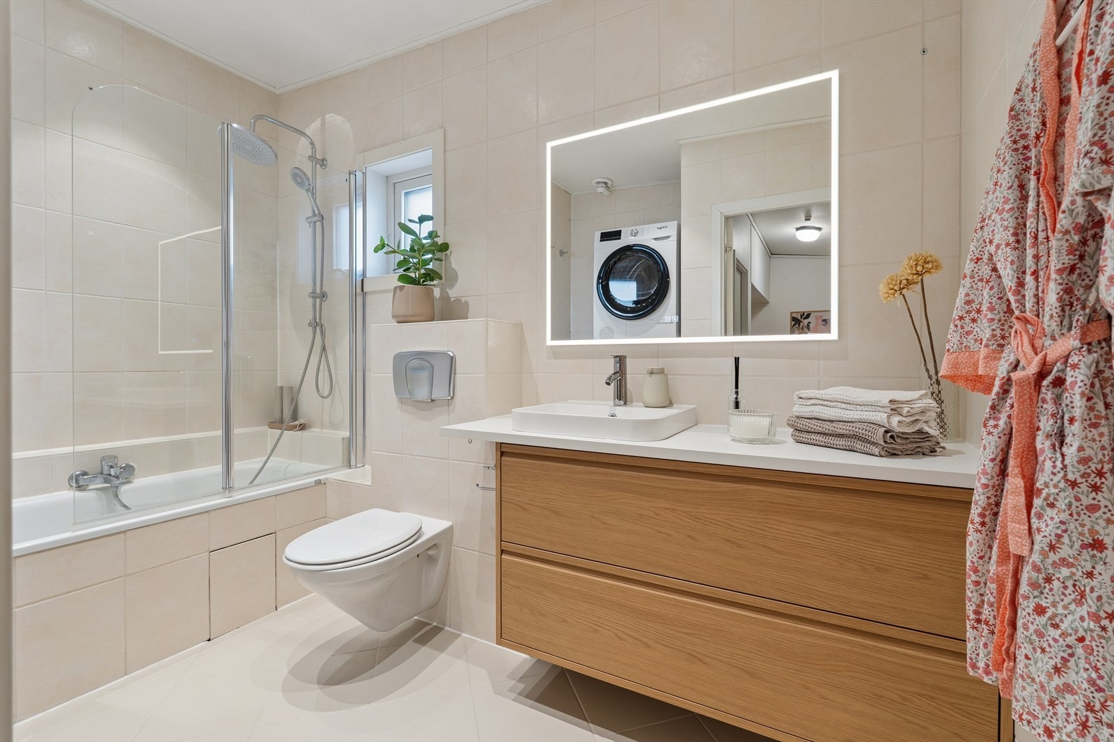 Badet er fra 2004 med flislagt gulv og vegger, innbygget badekar og vegghengt toalett Galleribilde
