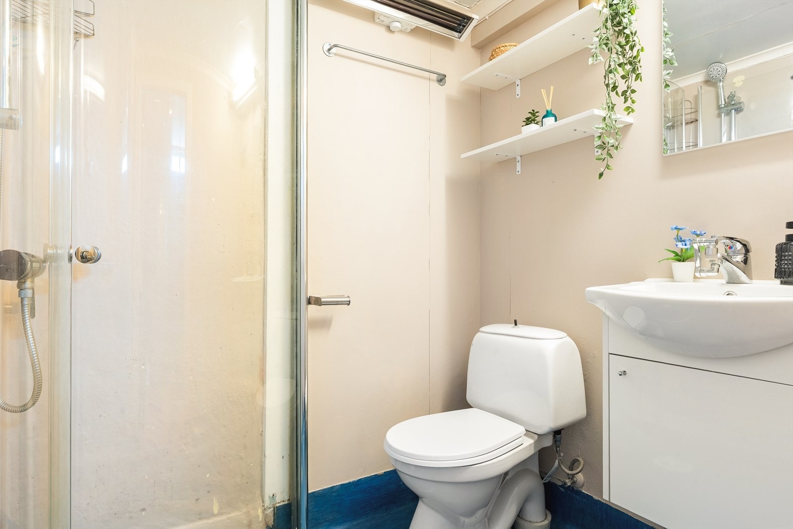 Badet i underetasjen har belegg på gulv og tapet på vegg. Innredet med toalett, dusj og servant møblement med speil. Galleribilde