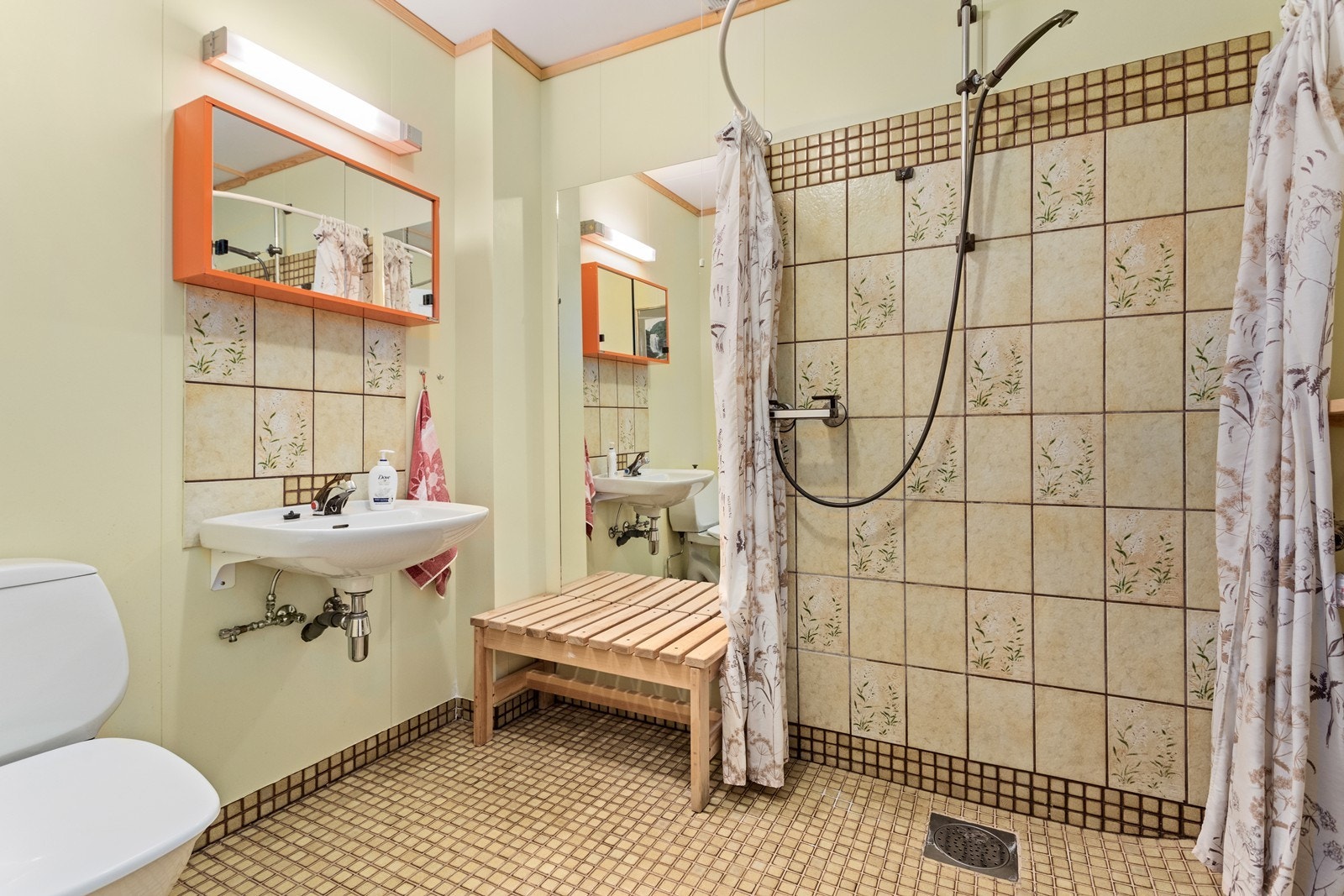 Badet i kjellaren har servant på vegg, golvmontert wc og dusj på vegg med forheng. Flisar på golv og i dusjsone, samt malte plater på veggar Galleribilde