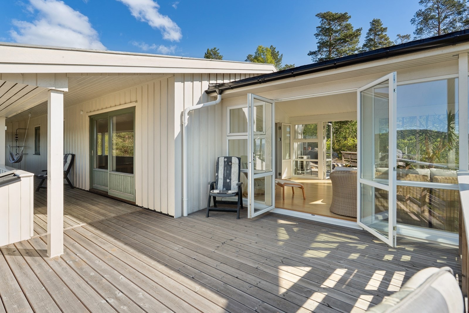 Altanen på fremsiden av huset strekker seg langs hele fasaden, og knytter sammen stue og vinterhage. Galleribilde