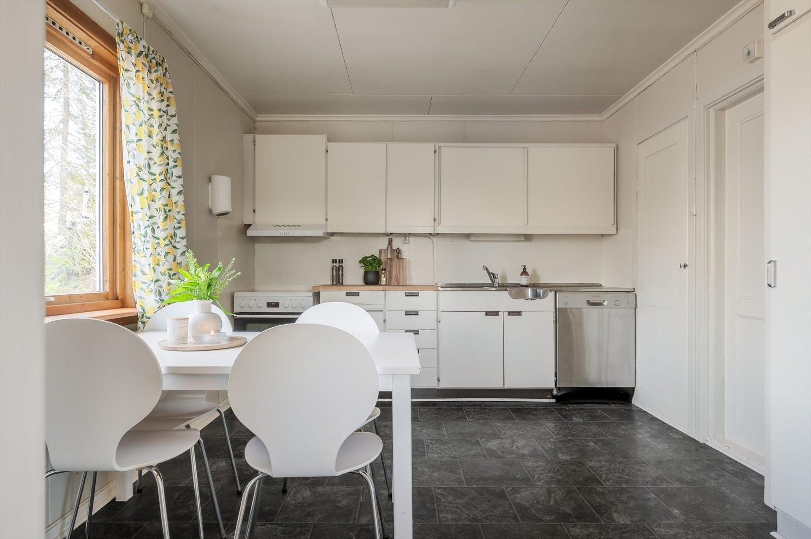 Eldre kjøkkeninnredning med lyse glatte fronter, laminert benkeplate og benkebeslag med nedfelt oppvaskkum. Galleribilde