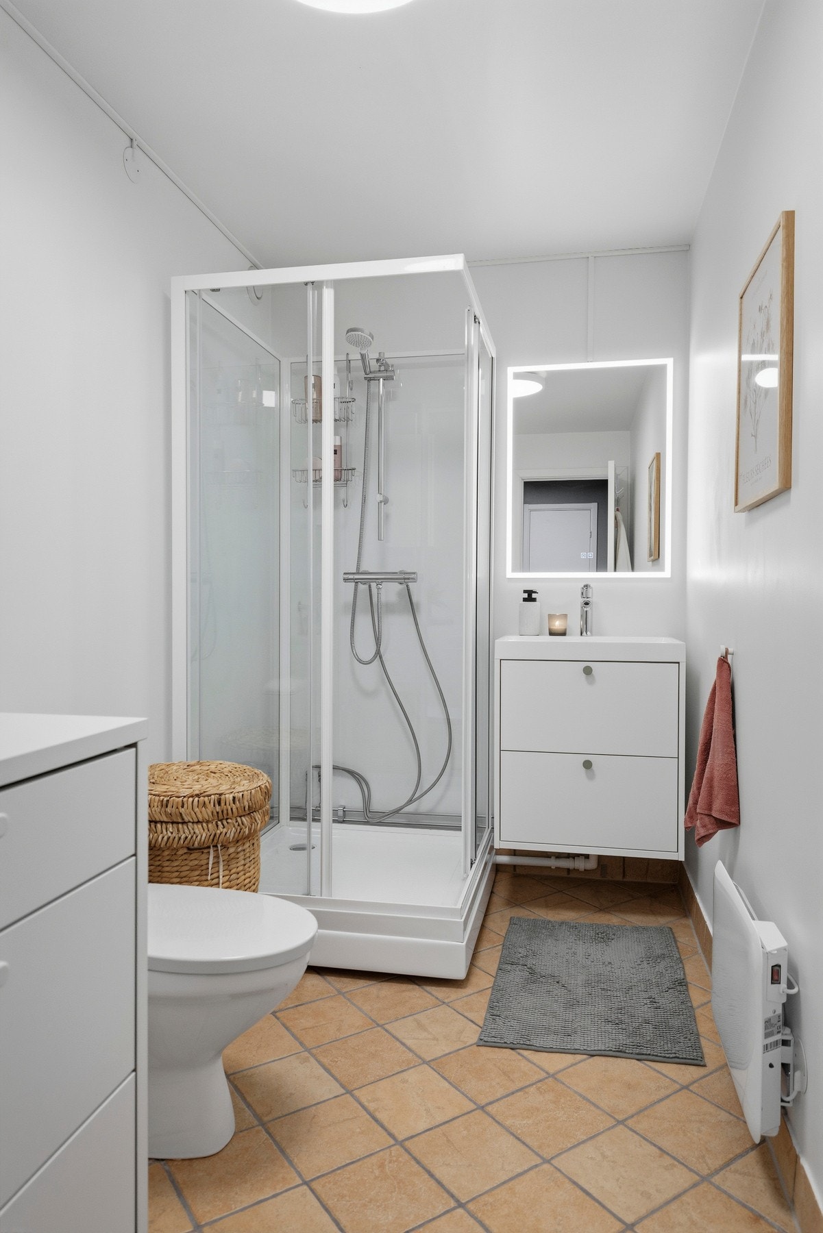 Badet er innredet med skap med glatte fronter, servant, klosett og dusjkabinett, samt opplegg for vaskemaskin Galleribilde