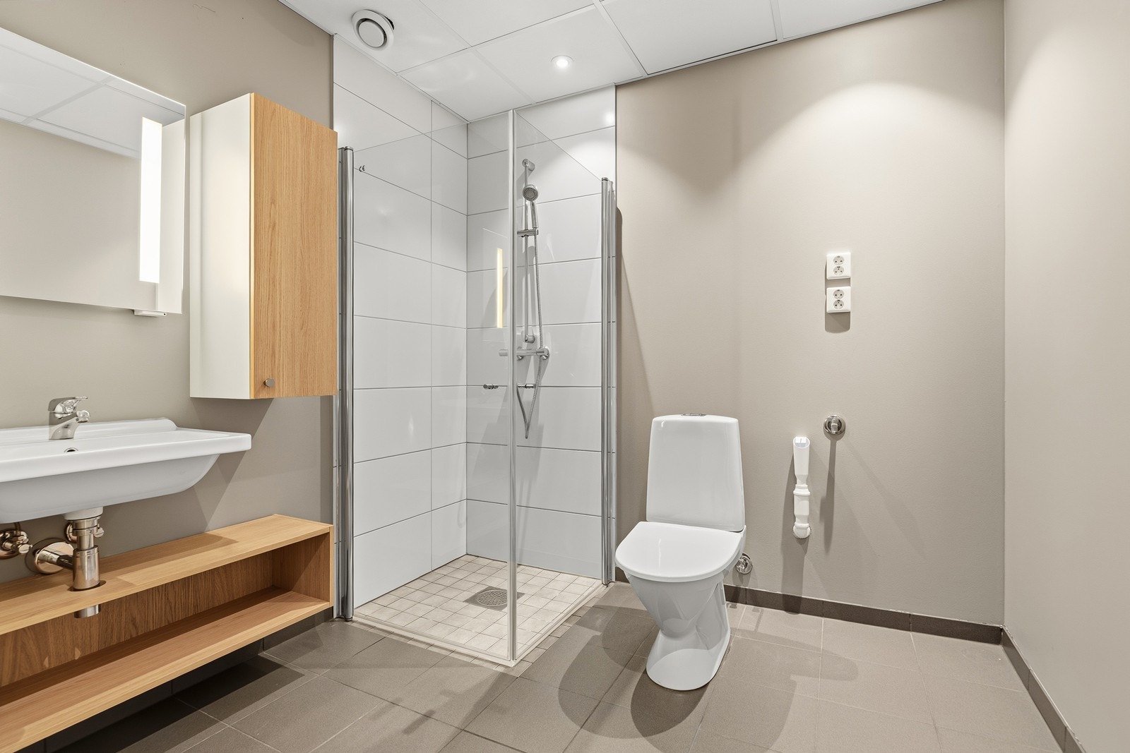 Badet er fra opprinnelig byggeår og inneholder dusjhjørne med glassdører, servantinnredning og toalett Galleribilde