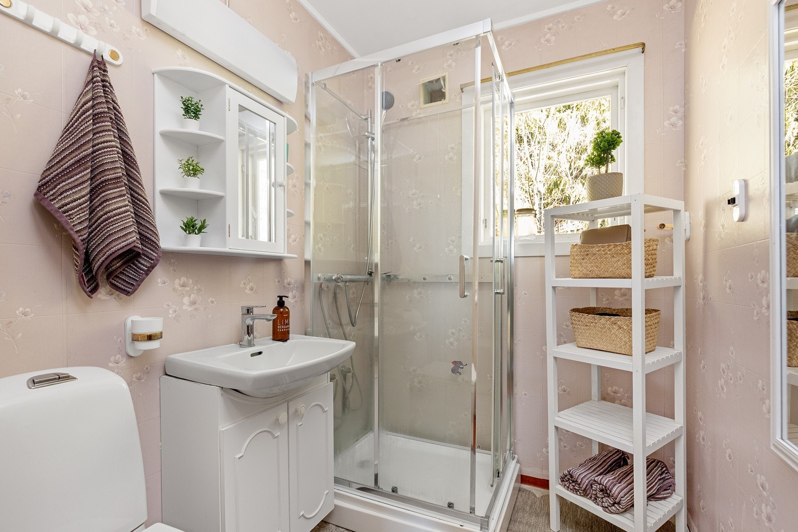 Badet har gulvbelegg og våtromstapet på vegger, samt servantinnredning med speilskap og dusjkabinett. Galleribilde