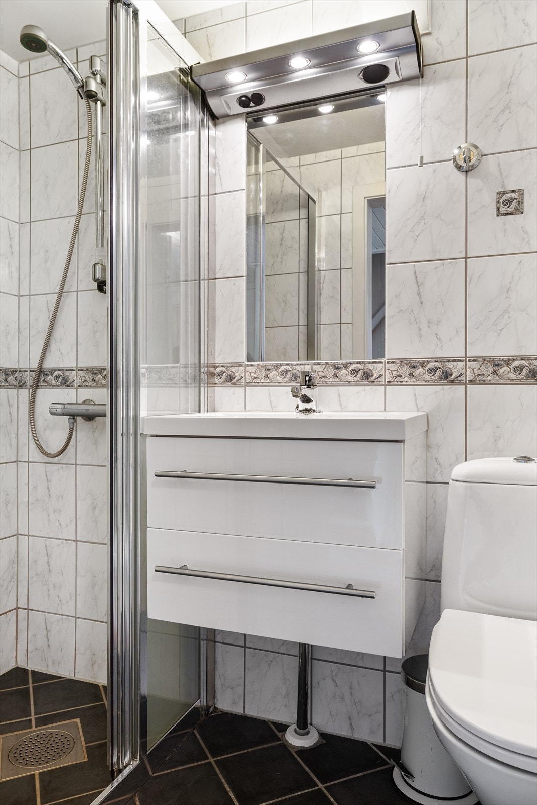 Badet i underetasjen har flislagt gulv med gulvvarme, dusjnisje, toalett og servant Galleribilde