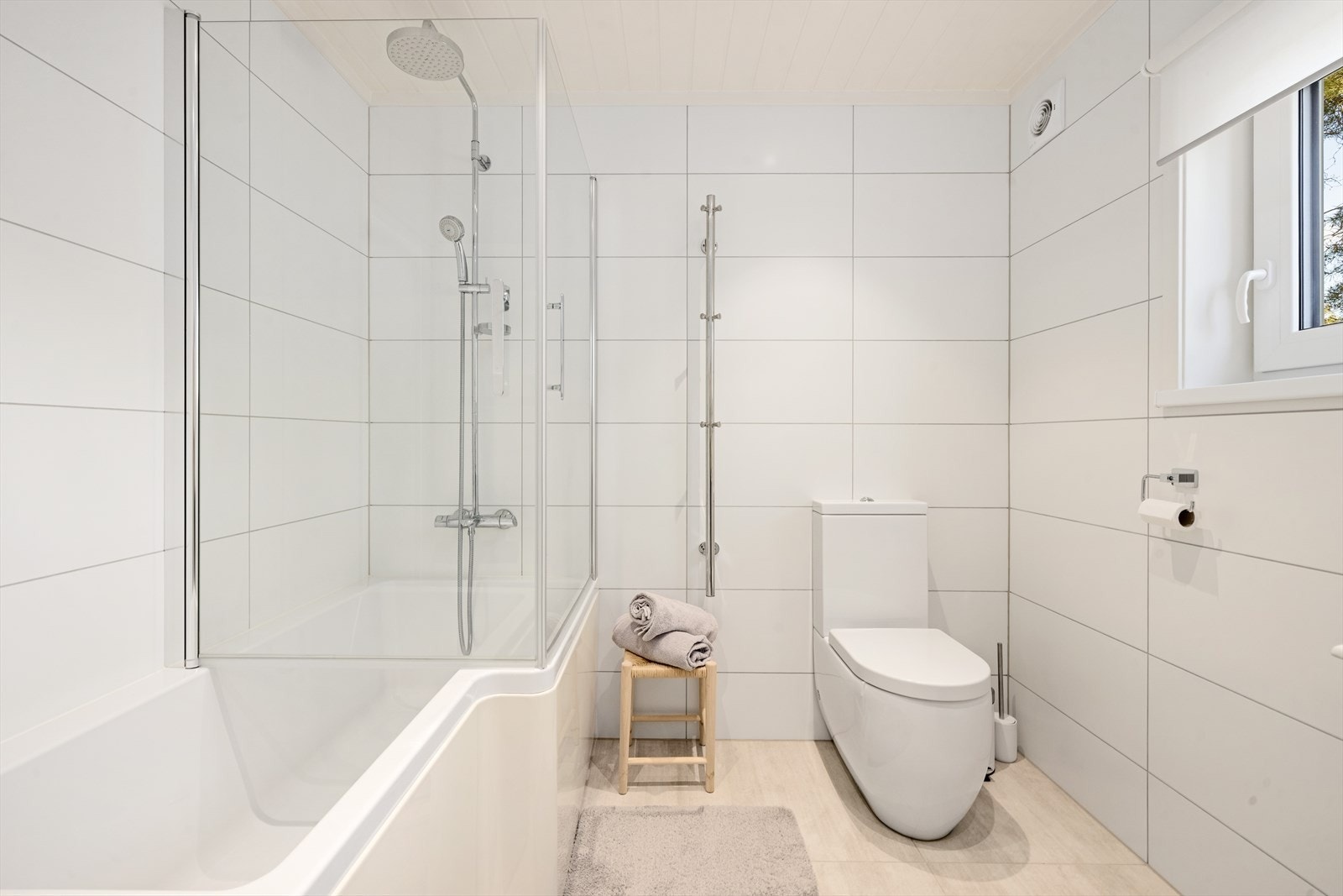 Badet er utstyrt med nedfelt servant over skuffeinnredning, speil, toalett og badekar i kombinasjon med dusj Galleribilde