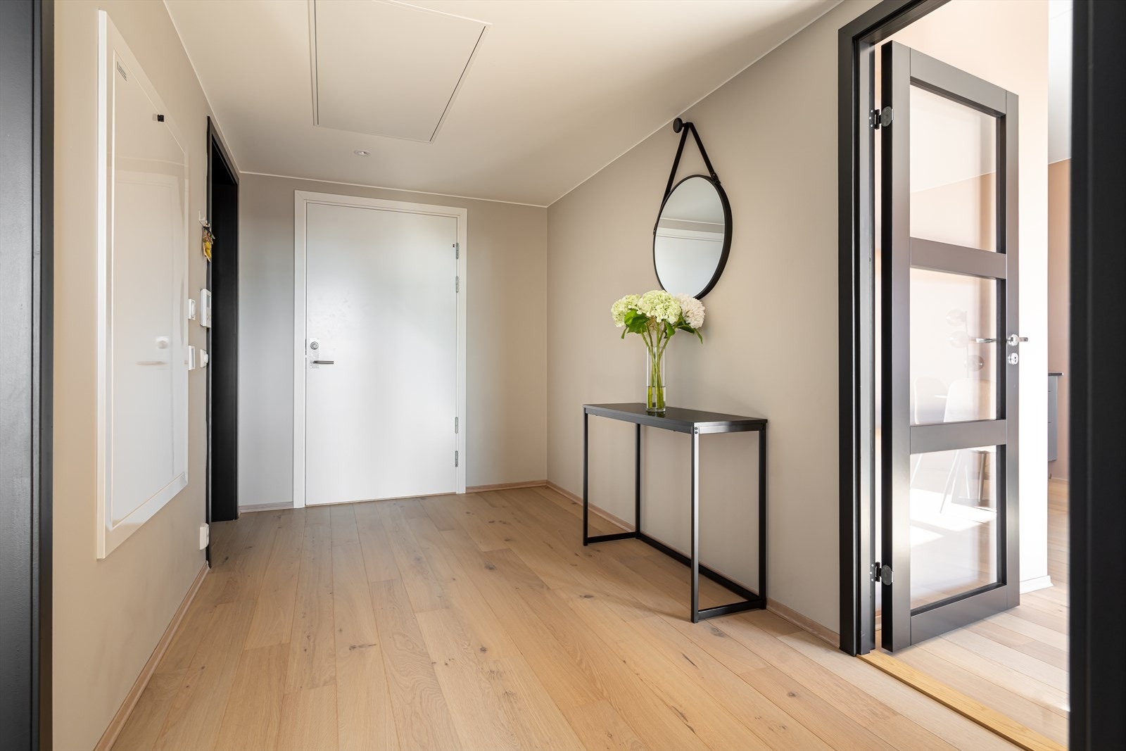 Vel inne er det god plass til å henge fra seg yttertøyet i en bred entré med downlights, beige vegger og 1-stavs parkettgulv. Galleribilde