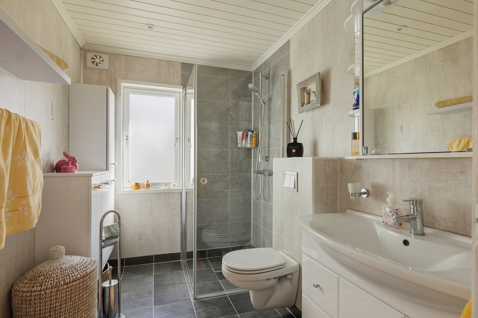Badet er totalrenovert i 2016 og inneholder nedfelt servant, veggmontert toalett og dusjvegger/hjørne Galleribilde