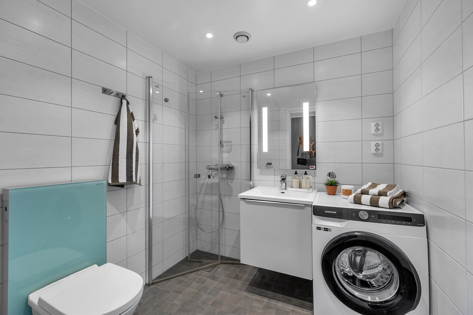 Pent, komplett flislagt bad, med moderne og praktiske innredninger og opplegg for vaskemaskin. Galleribilde