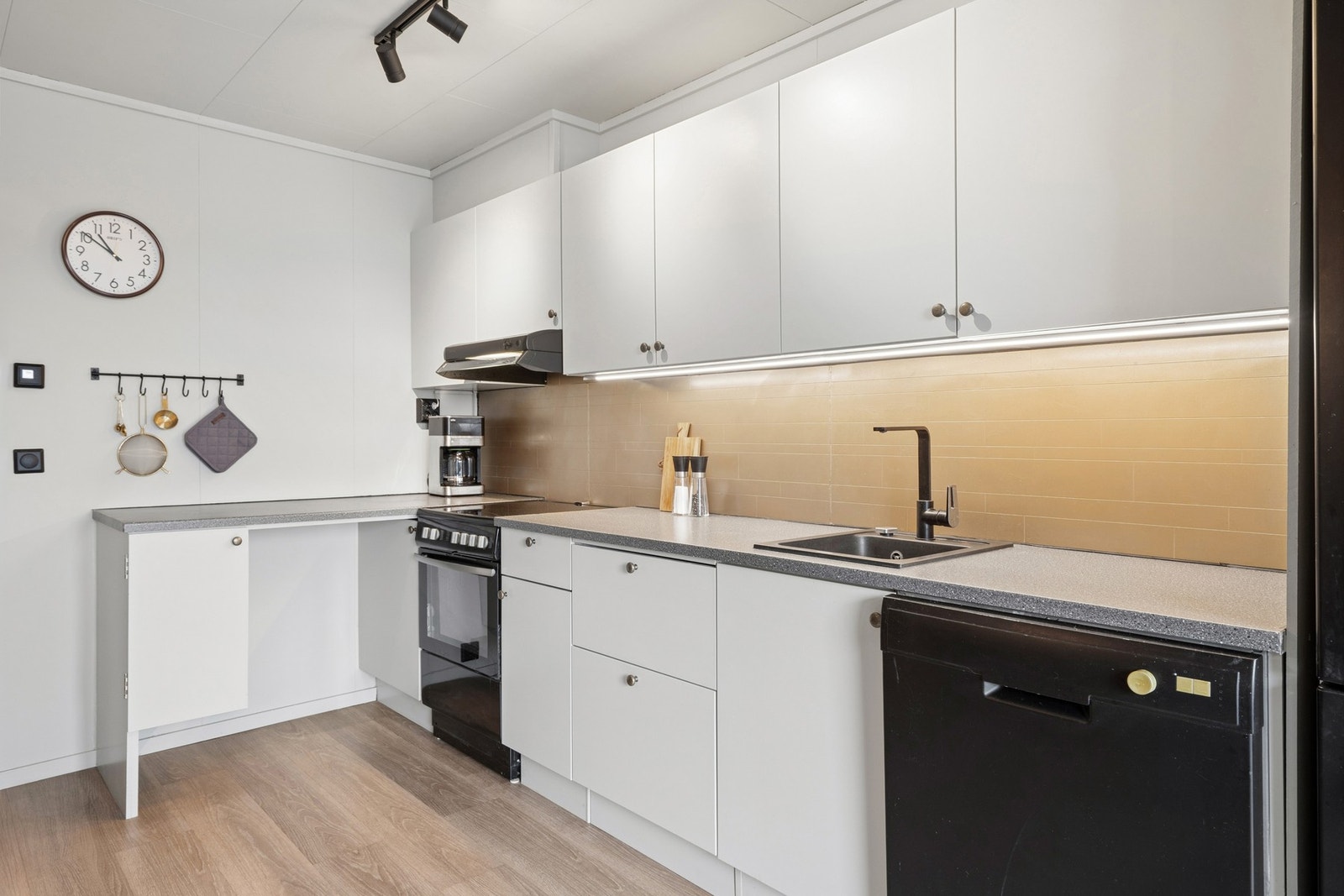 Kjøkkenet er utstyrt med komfyr, oppvaskmaskin og nedfelt kum i laminatbenkeplaten. Galleribilde