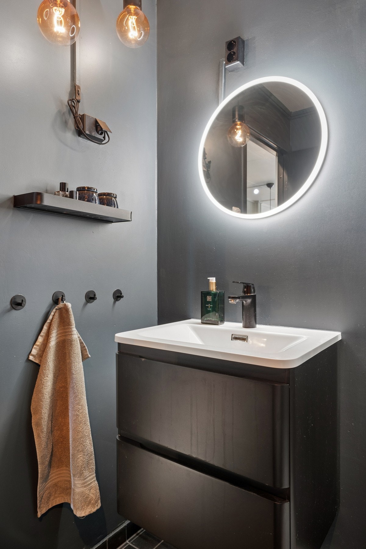 Badet er innredet med servant med underskap, speil med integrert belysning og vegghengt hylle. Galleribilde