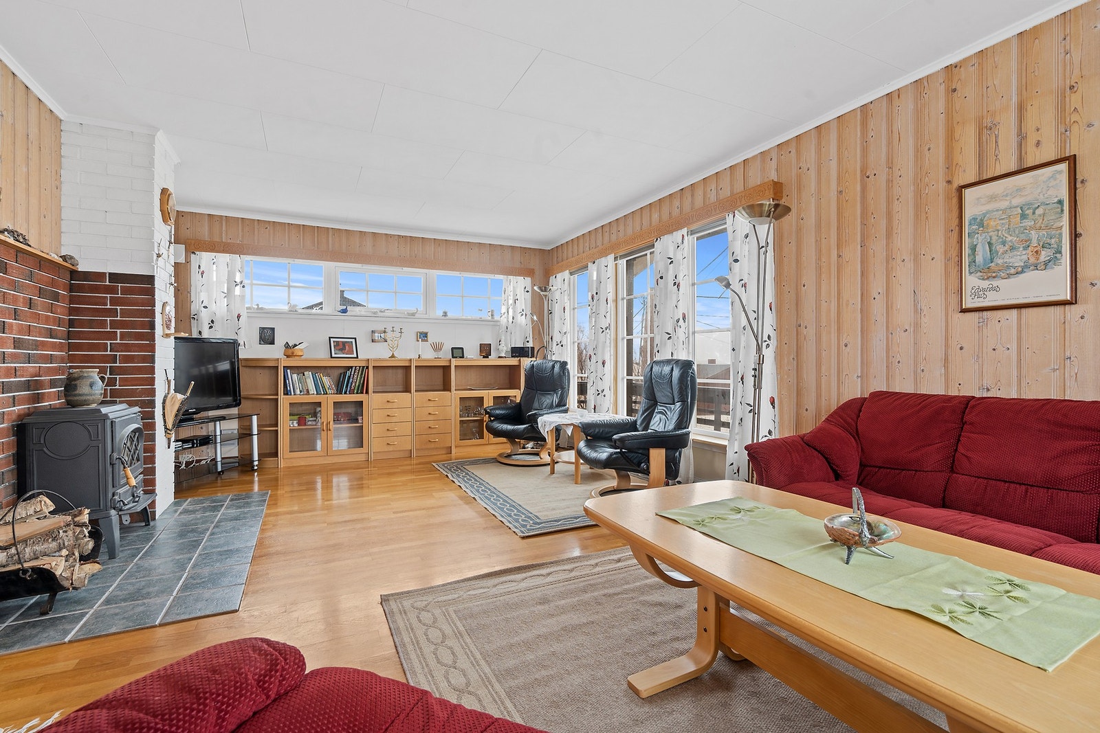 Stuen har parkett på gulvet og vegger med en kombinasjon av trepanel og malte plater. Galleribilde