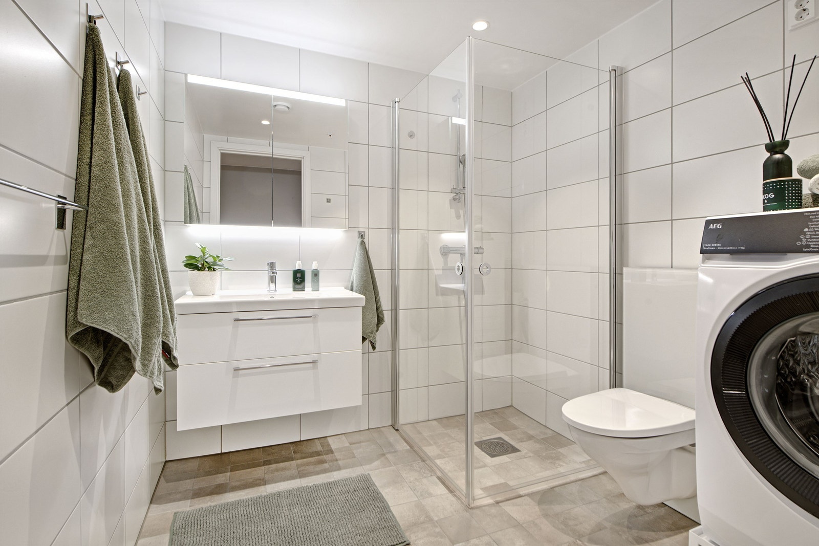 Bad - lekkert bad med flislagt gulv og vegger - gulvvarme - downlights i himling - baderomsinnredning - dusjhjørne - vegghengt toalett - opplegg for vaskemaskin Galleribilde