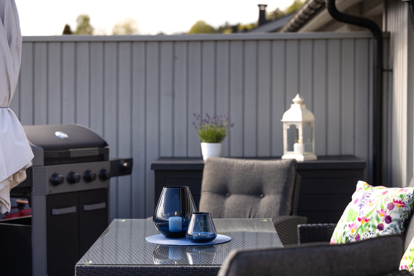 Uteplass med grill og sittegruppe, omgitt av grå vegger. Galleribilde