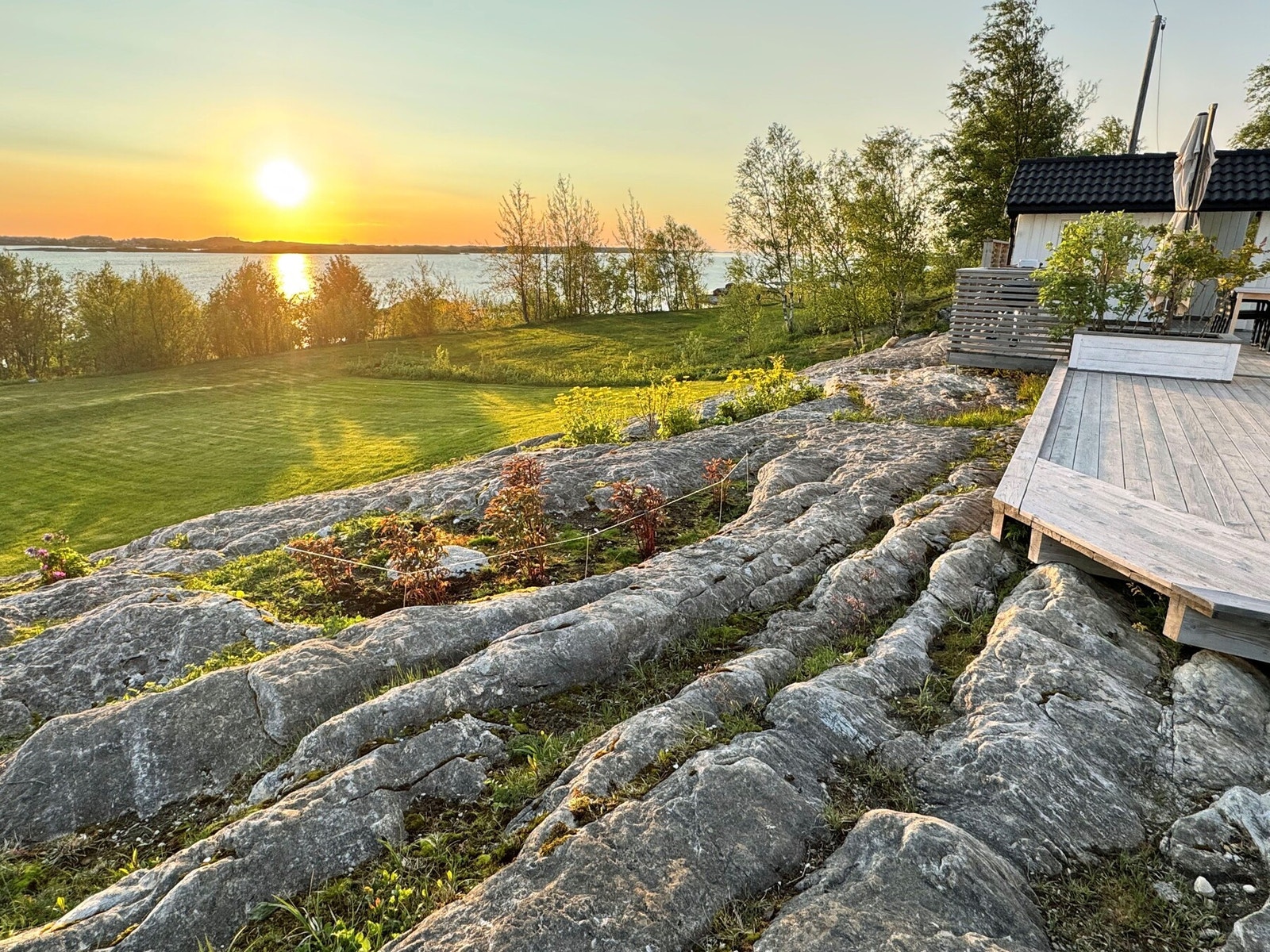 Tomten er svakt kupert og opparbeidet med plen, beplantning og naturlige svaberg. Galleribilde