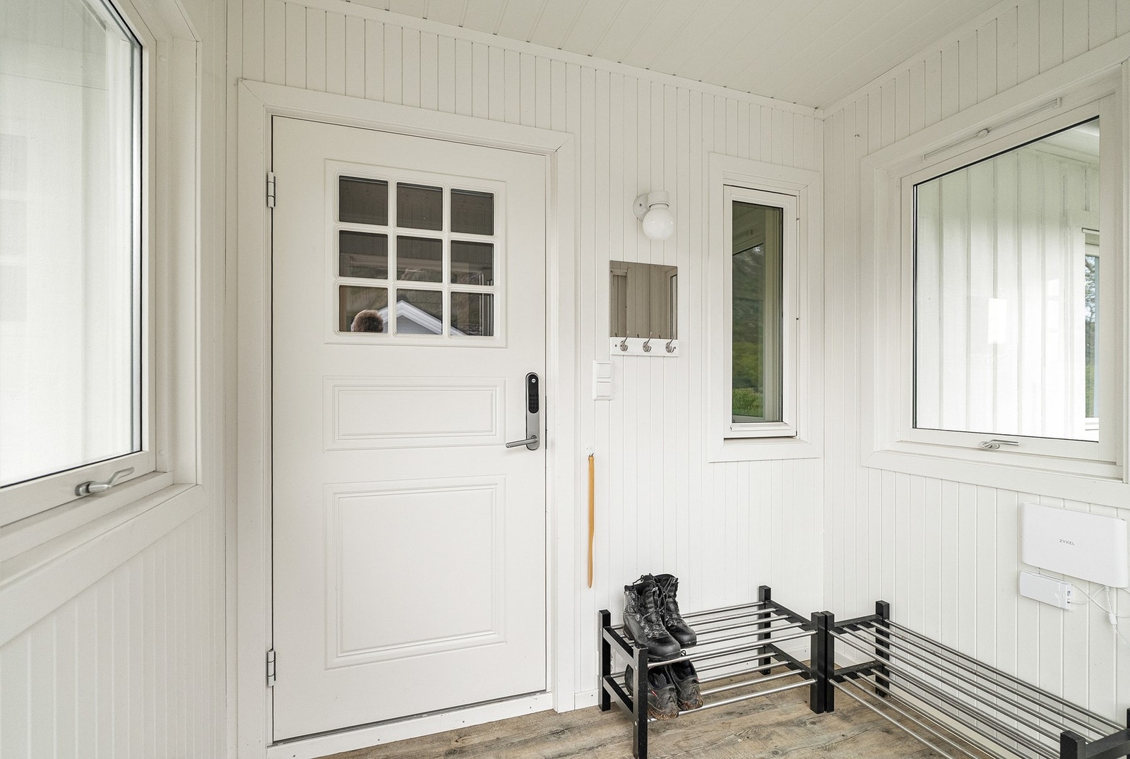 Overbygget inngangsparti med skyvedør i glass og hoveddør med elektronisk lås. Galleribilde
