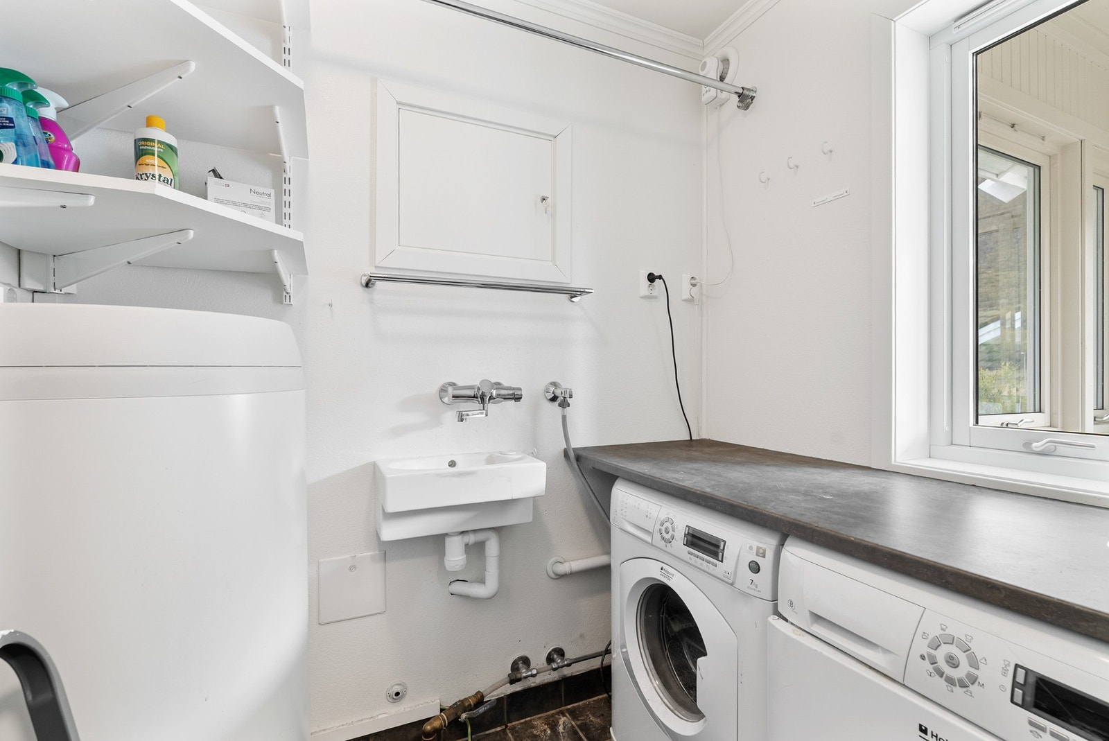 Praktisk vaskerom med flislagt gulv, opplegg for vaskemaskin og en 200-liters varmtvannsbereder. Galleribilde
